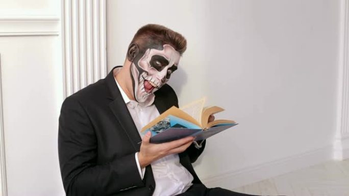 一个有着可怕的头骨化妆的男人手里拿着一本书。