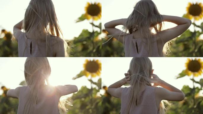 可爱的金发女孩站在一大片田野里，夏天有黄色的向日葵。