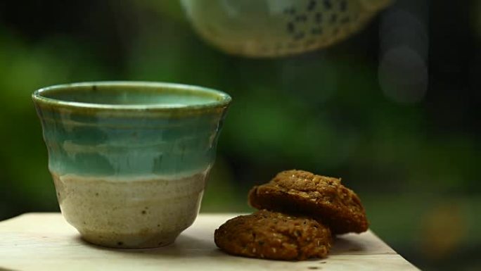 杯中的茉莉花绿茶和木桌上的饼干。
