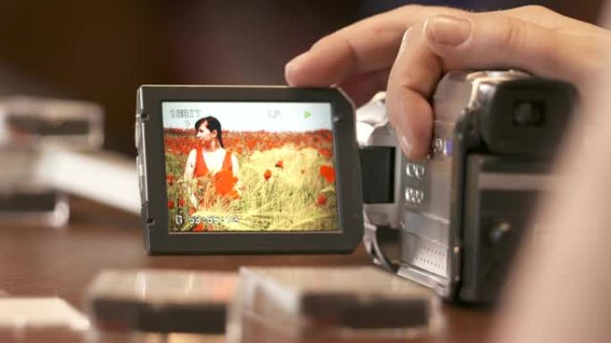 男子在数字迷你数码摄像机的液晶显示屏上观看家庭家庭视频