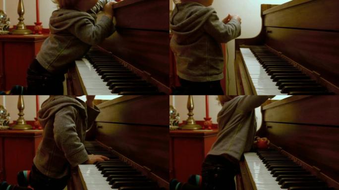 高加索蹒跚学步的男孩和妈妈坐在钢琴上，在钢琴上弹奏，身后有一棵装饰好的圣诞树