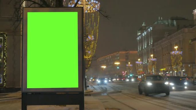 繁忙的节日街道上有绿屏的广告牌。