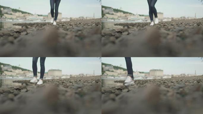 苗条女士的脚在河边的岩石上行走