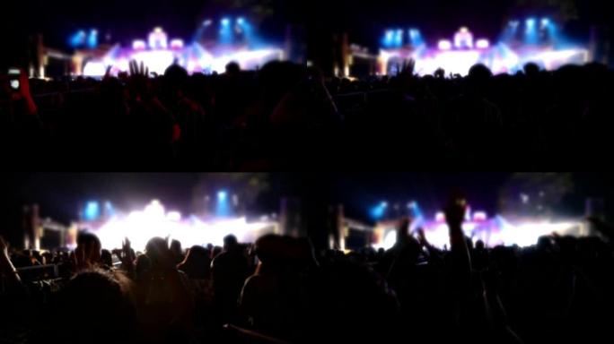 节日人群后视音乐会人群轮廓的慢动作在明亮的舞台灯光上举手