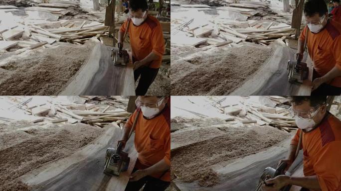 一个木匠正在工厂里磨一块大木板