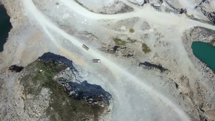在露天采矿坑中行驶在土路上的建筑卡车的空中静态视图