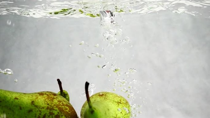 梨子掉进水里，有很多气泡。孤立的白色背景上的水果。