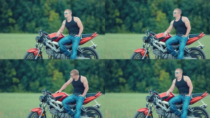 美丽的摩托车手坐在模糊背景上站在摩托车座位的侧面