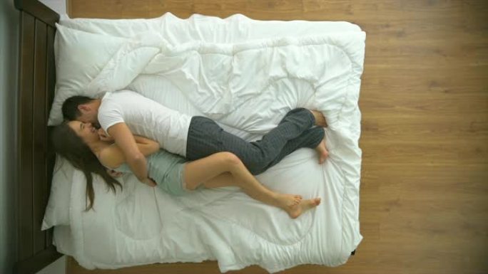快乐的男人和女人在床上玩耍。从上方观看，慢动作