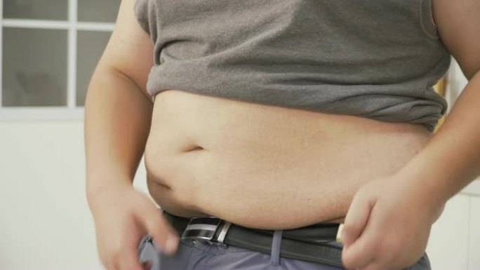 侧视图: 超重男子检查肚子上的体重