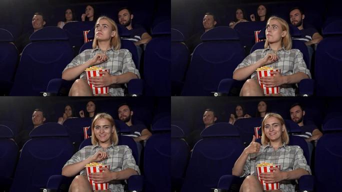 年轻迷人的女人在电影院微笑着竖起大拇指