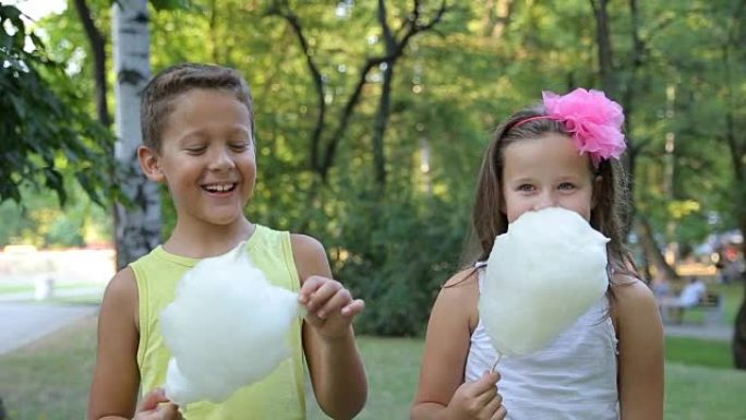 一个男孩和一个女孩吃棉花糖，微笑着