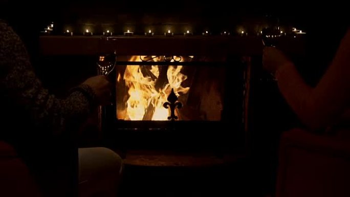 年轻夫妇在舒适的壁炉旁用白葡萄酒碰杯