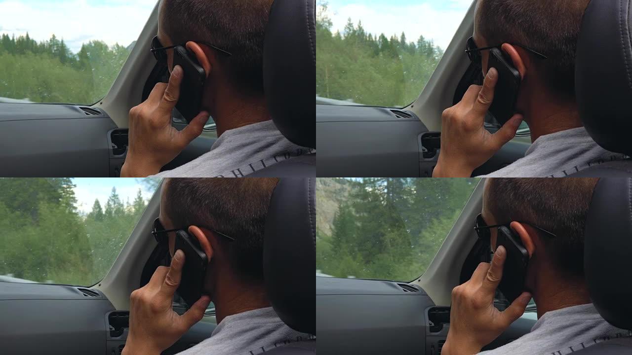 从汽车后座看，一个年轻人在用手机说话。