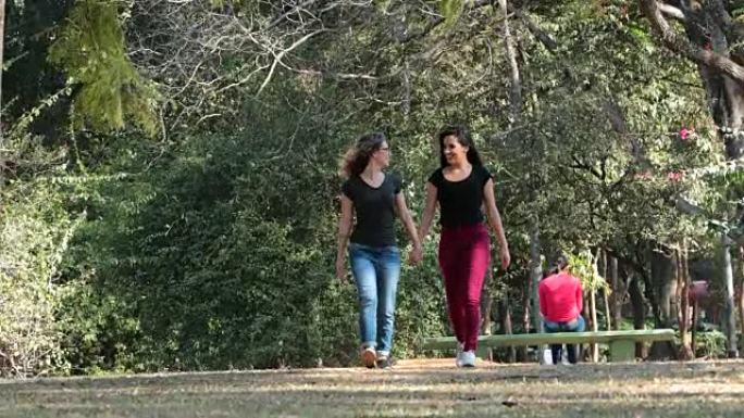 两个女朋友一起牵着手在公园散步