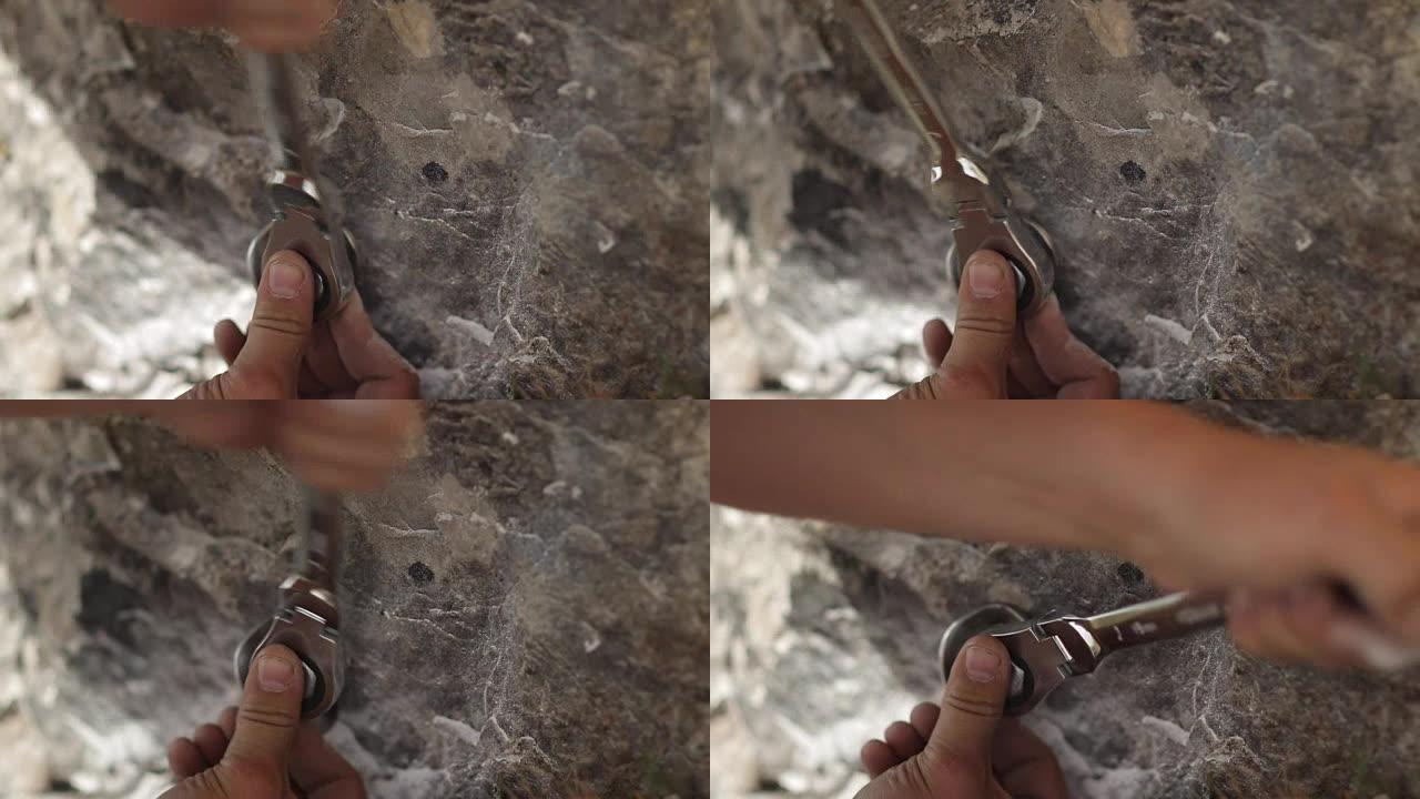 该名男子的手将钥匙螺栓拧入岩石的特写镜头。