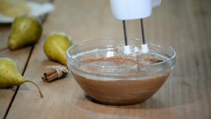 巧克力面团在玻璃碗中与搅拌机混合。制作巧克力梨蛋糕。