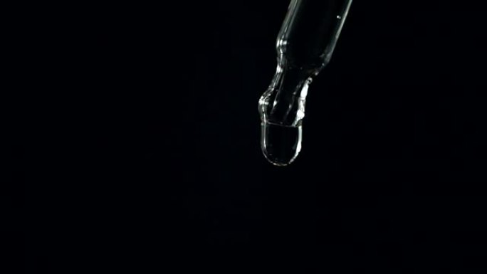 移液器中的液体缓慢运动在黑色背景上滴落