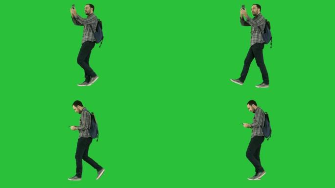 年轻迷人的学生背包客游客在绿屏上用手机自拍照片，色键