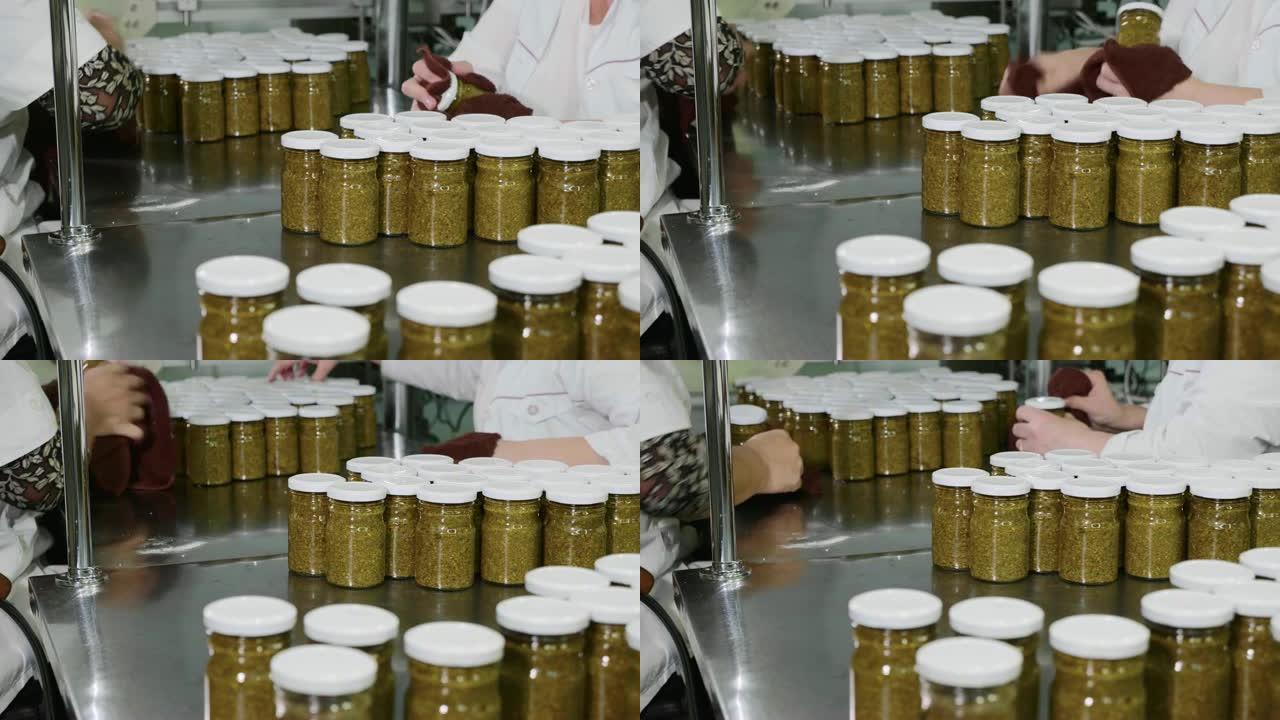 工人在传送带上打上烙印之前先用香蒜酱擦拭玻璃罐，特写镜头