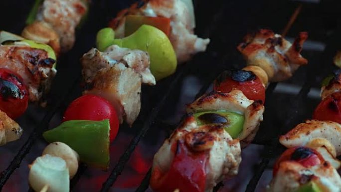 在烧烤架上的竹签上烹饪新鲜蔬菜和腌制的肉，并带有火和吸烟特写