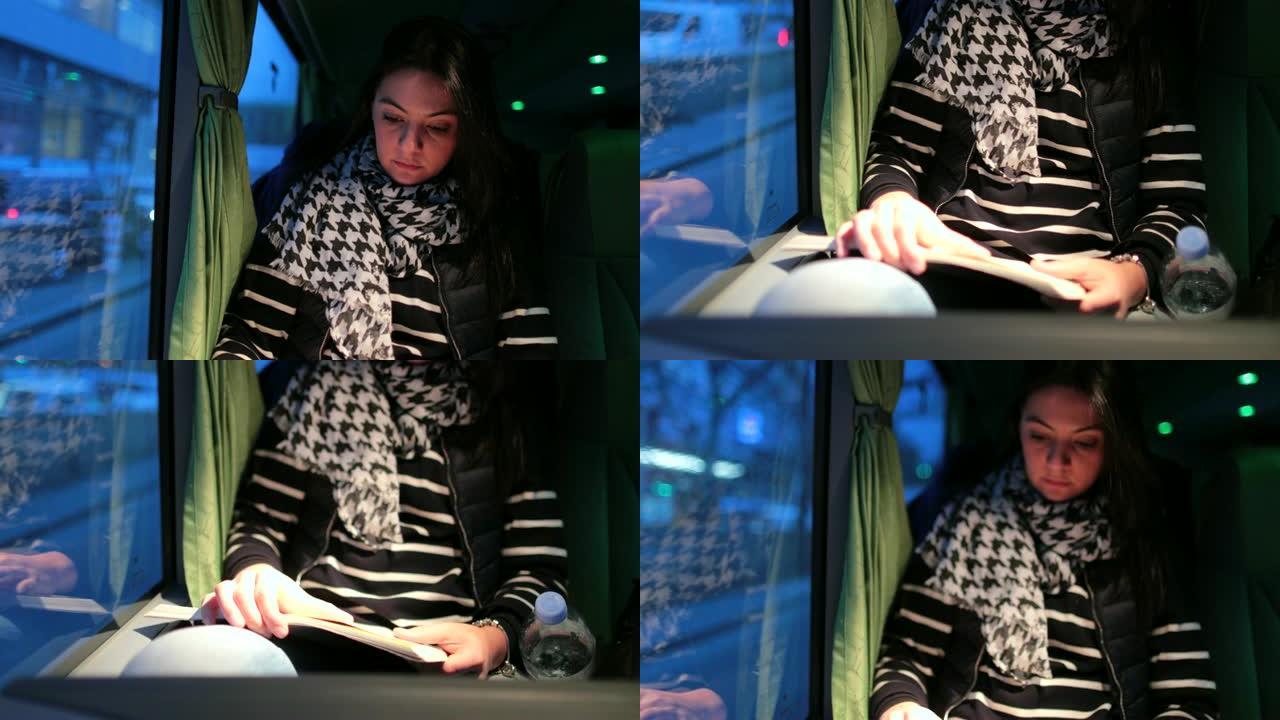 晚上乘公共汽车旅行的女乘客看书。晚上，女孩在窗户旁边的行驶车辆上读故事