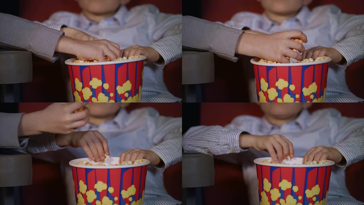 孩子们用手从纸盒里拿出爆米花。儿童电影食品
