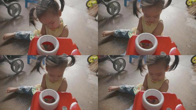 一个快乐的亚洲小美女喜欢和2岁的法国斗牛犬在地板上玩玩具。幸福、活力、嬉戏的概念。