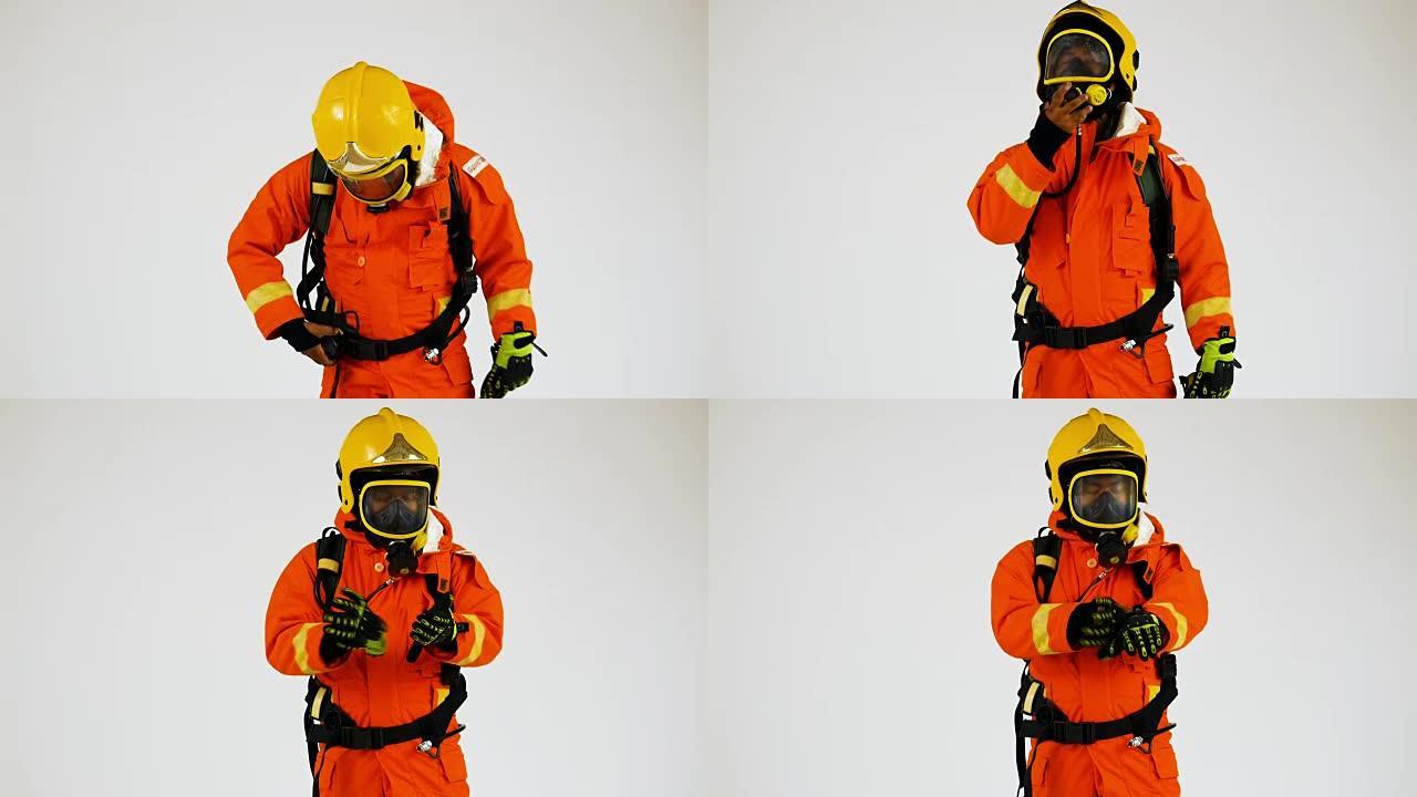 身穿橙色防火制服的消防员戴着白色背景上的帽子和面具