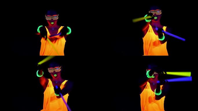 女人用UV面漆，发光的衣服，发光的眼镜，手镯在镜头前跳舞，手持化学光，半身拍摄。亚洲女人。。