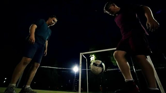 两名年轻男子晚上在场上交替踢球