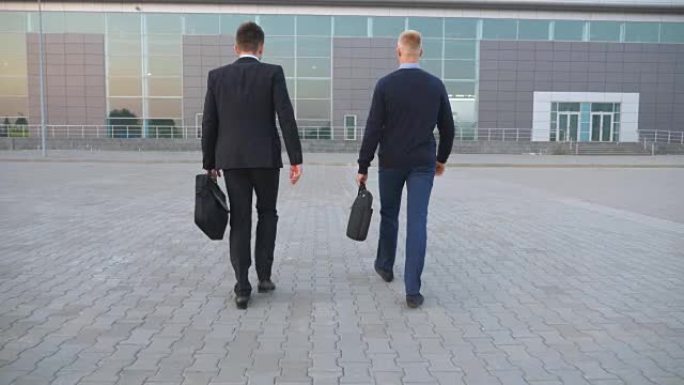 两个面目全非的年轻商人穿着正装，带着公文包去办公中心。自信的经理们带着行李去曼城工作。成功的同事通勤
