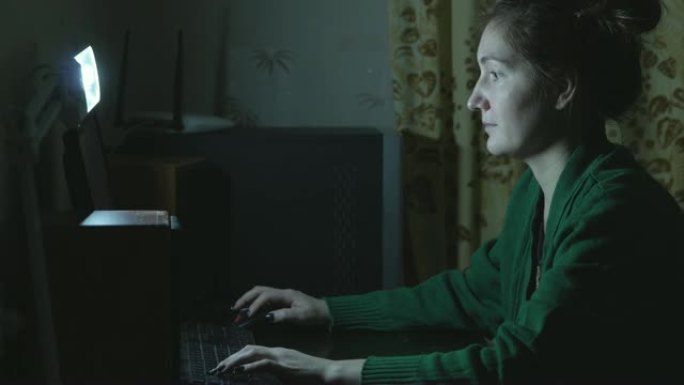 晚上在家用电脑工作的女人。