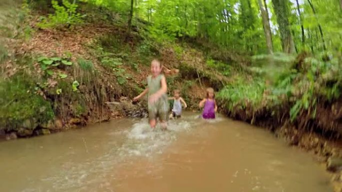 三个女孩在森林里的一条小溪里奔跑和散步，笑着