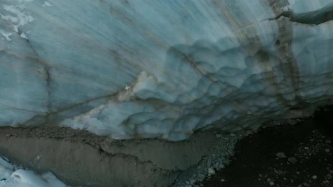 鸟瞰图特写边缘流动的冰川覆盖着高山上的雪和石头。冰川融化的自然破坏和全球变暖