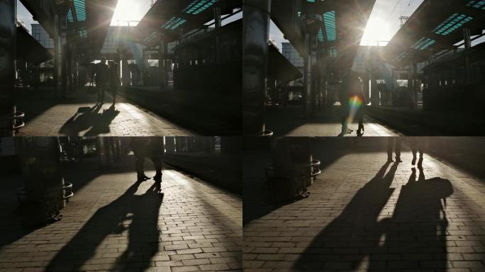 在最后的阳光下，在火车站的站台上告别年轻的情侣。火车站站台上年轻情侣的剪影。