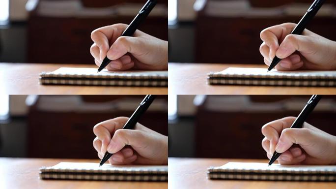 女人的慢动作在木桌上的空白笔记本上书写