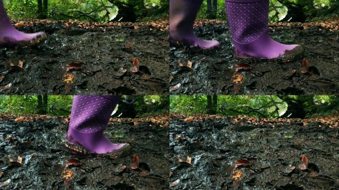 年轻女孩带着雨靴穿过泥泞的水坑