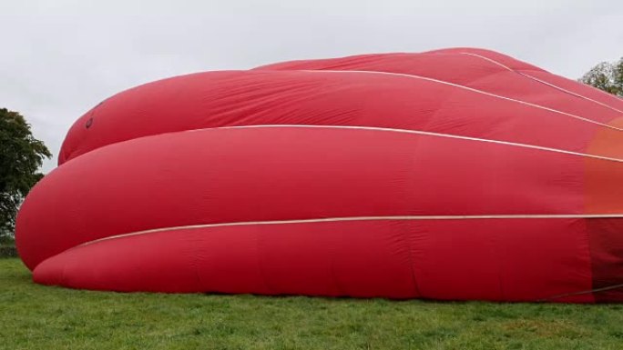 4K: 热气球 (红色) 在地面上缓慢充气-从侧面