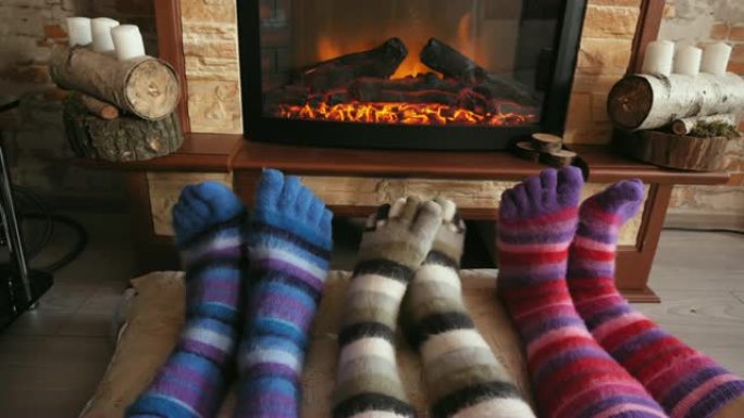 穿着羊毛有趣的袜子的脚在圣诞节用舒适的火取暖