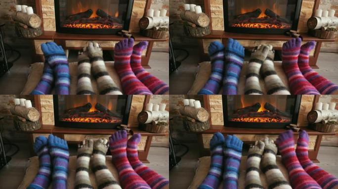 穿着羊毛有趣的袜子的脚在圣诞节用舒适的火取暖