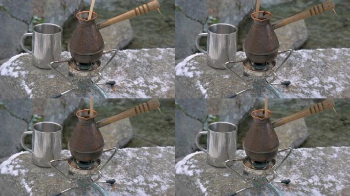 在河岸上的山区便携式燃气燃烧器上煮咖啡。
