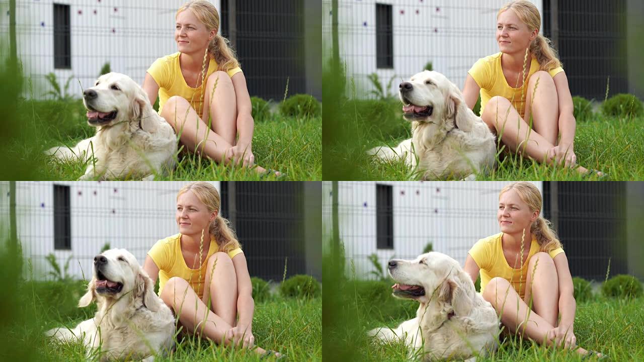 对宠物的爱 -- 一个年轻的金发女人和她的狗在草地上休息