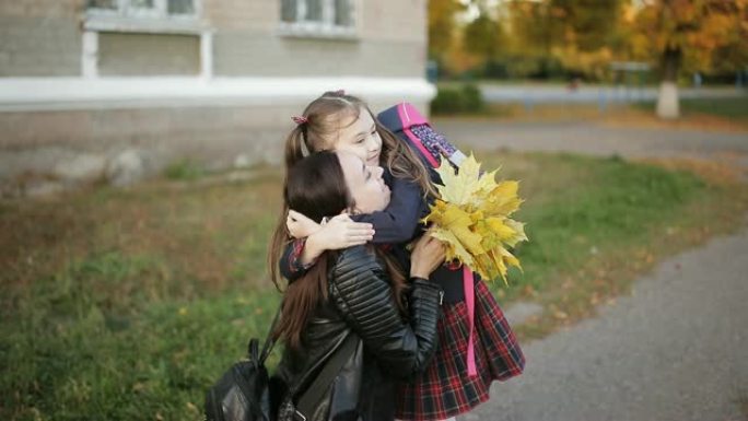 母女放学后在学校附近拥抱。妈妈从学校接女儿。