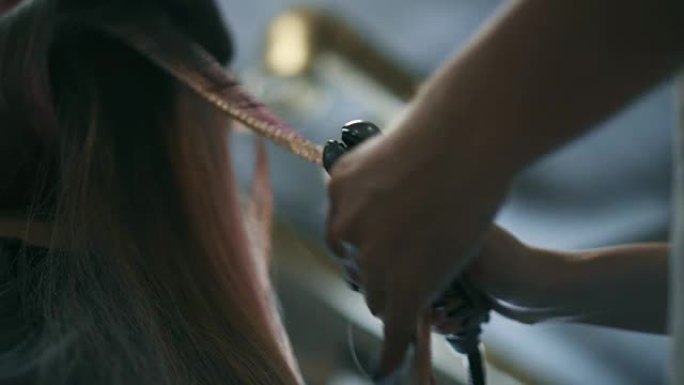 理发师用钳子做波浪状的头发。底视图