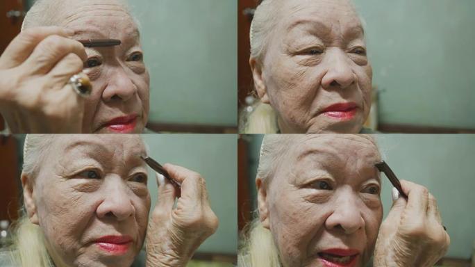 年长的女士在涂面霜、睫毛膏、口红。在家化妆。概念:美丽,生活