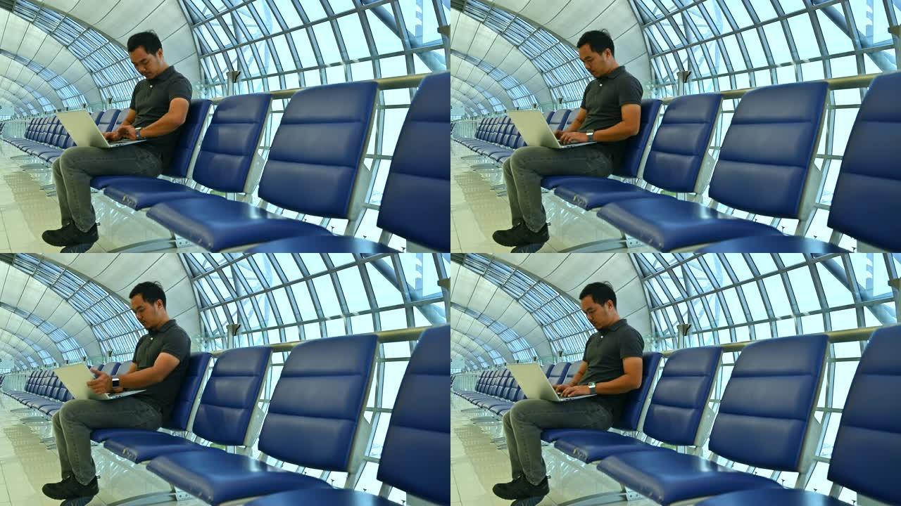 亚洲男性在国际机场等待飞行时使用笔记本电脑