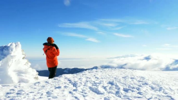 女性高山登山者在冬季日出时在高海拔山峰上喝咖啡