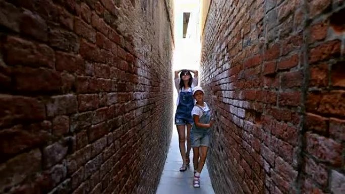 意大利威尼斯-2018年7月7日: 沿着威尼斯非常狭窄的街道，在老房子之间，一个十几岁的女孩，孩子和