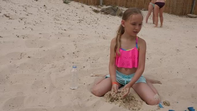 可爱的女孩子玩沙子坐在沙滩上